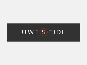 Logo Uwe Seidl in Farbe auf grauem Hintergrund